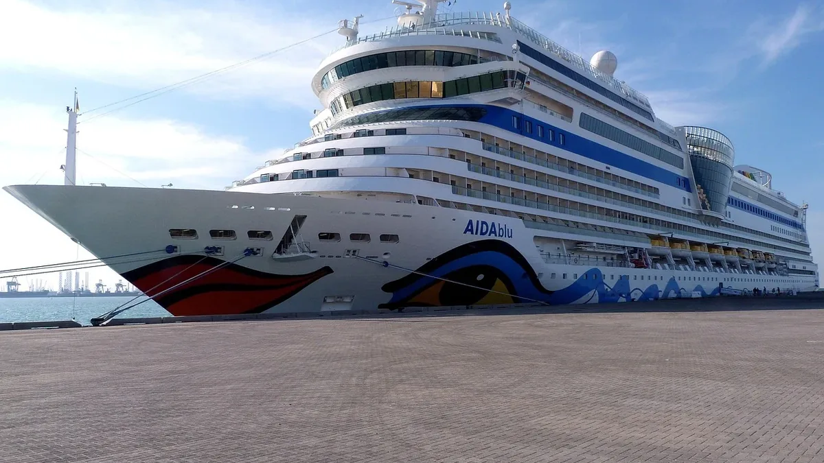 A large cruise ship docked at a port, with the ship's name "AIDAnova" visible on its side.