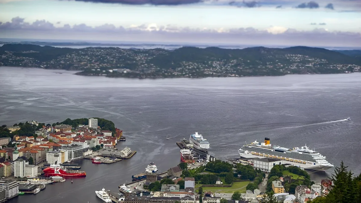A city situated on the edge of a large body of water, with several boats and ships visible in the harbor.