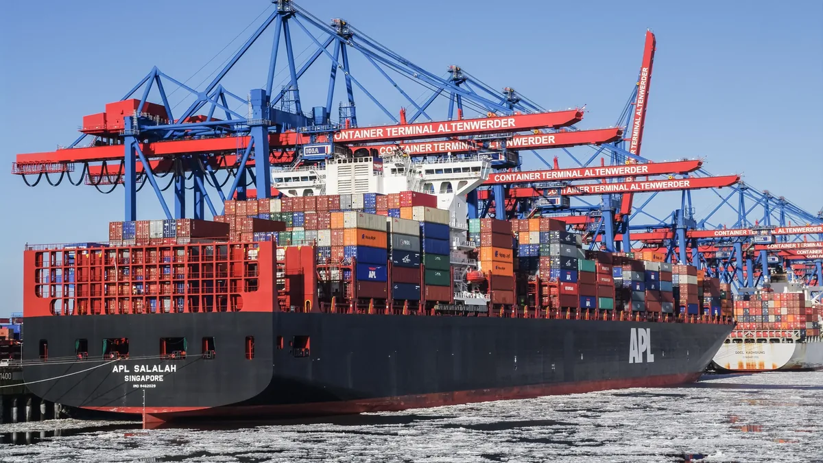 A large cargo ship, the APL BALALAN, docked at a busy port with multiple cranes and containers visible.